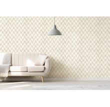 Obývací pokoj s geometrickou tapetou ve stylu chevron, světlou čalouněnou pohovkou a minimalistickým závěsným svítidlem.