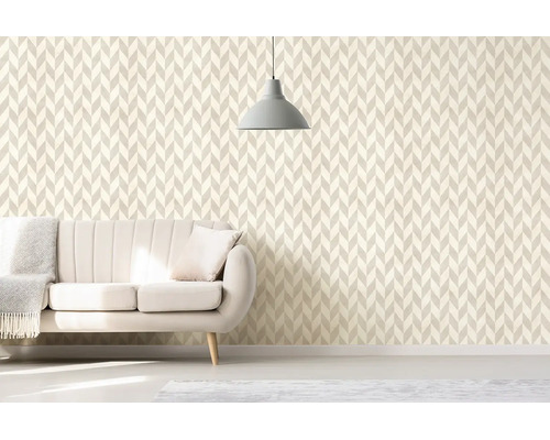 Obývací pokoj s geometrickou tapetou ve stylu chevron, světlou čalouněnou pohovkou a minimalistickým závěsným svítidlem.