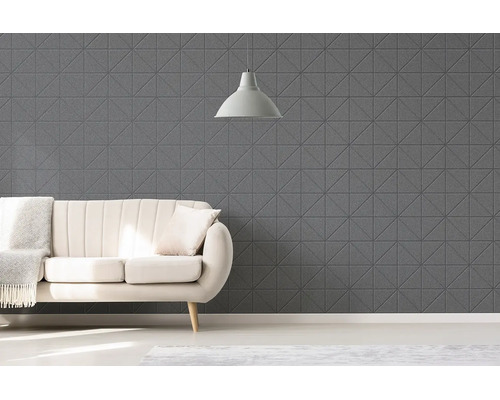 Moderní obývací pokoj s geometrickými strukturovanými stěnovými panely, pohovkou s přehozem a závěsným svítidlem.