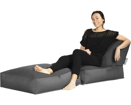 Dvoudílná lounge sestava sedacích vaků skládající se z křesla s opěradlem a taburetu, na kterém sedí žena.
