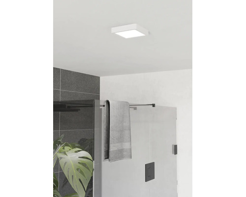 Čtvercové stropní LED svítidlo v moderní koupelně nad skleněným sprchovým koutem s černým kováním a tmavě šedými obklady.