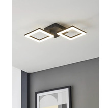 Moderní stropní LED svítidlo se dvěma čtvercovými černými rámy, namontované na bílém stropě nad šedou stěnou s rámovaným obrazem.