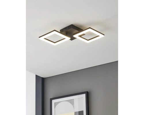 Moderní stropní LED svítidlo se dvěma čtvercovými černými rámy, namontované na bílém stropě nad šedou stěnou s rámovaným obrazem.