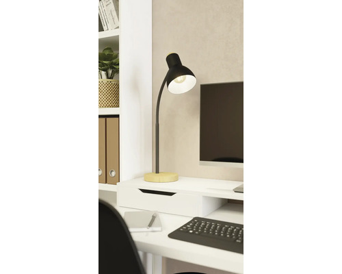 Moderní stolní lampa z černého kovu s dřevěným podstavcem na bílém pracovním stole ve světlém, organizovaném pracovním prostoru.