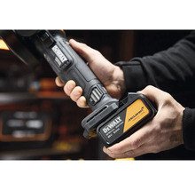 Ruce vkládají akumulátor DeWalt 18 Voltů 5 Ampérhodin McLaren Special Edition do akumulátorového nářadí.