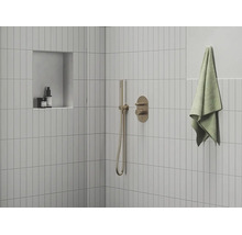 Moderní sprcha s úzkými obklady, podomítkovou baterií, tyčovou ruční sprchou a nikou v minimalistické koupelně.