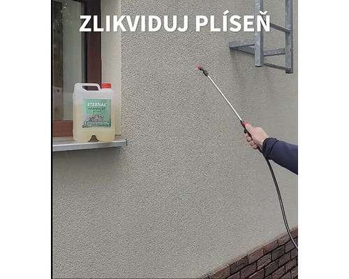 Osoba aplikuje postřik proti plísním na fasádu pomocí tlakového postřikovače, vedle stojí kanystr s přípravkem Eternal na likvidaci plísní.