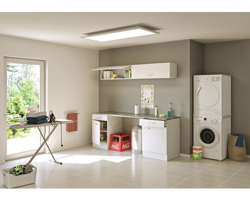 Světlá prádelna s pračkou, sušičkou, žehlicím prknem, nástěnnými skříněmi a osvětlením