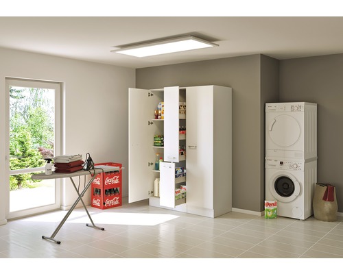 Světlá prádelna s pračkou, sušičkou, žehlicím prknem a vysokou skříní s policemi