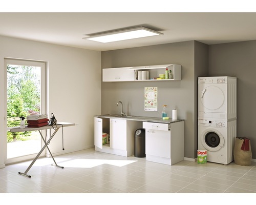 Světlá prádelna s pračkou, sušičkou, žehlicím prknem a umyvadlem