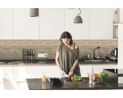 Moderní kuchyně s dřevěnými panely a žena krájející zeleninu