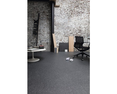 Interiér s tmavou podlahou, kancelářská židle a bílý stůl před cihlovou zdí