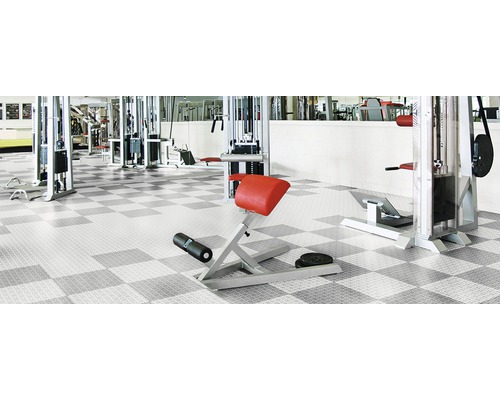 Posilovna se sportovním vybavením a podlahovou krytinou se šachovnicovým vzorem