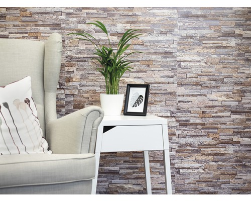 Stěnový obklad PVC Ceramics StoneWall sand KR 67,5x400 cm Dekorativní kamenná stěna s křeslem, stolem a pokojovou rostlinou pro útulné prostředí.