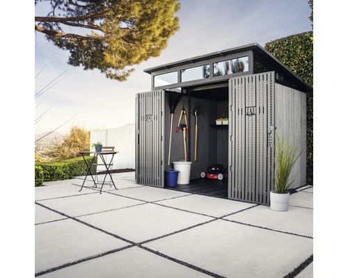 Zahradní kůlna s otevřenými dveřmi a zahradním nářadím na zahradě.