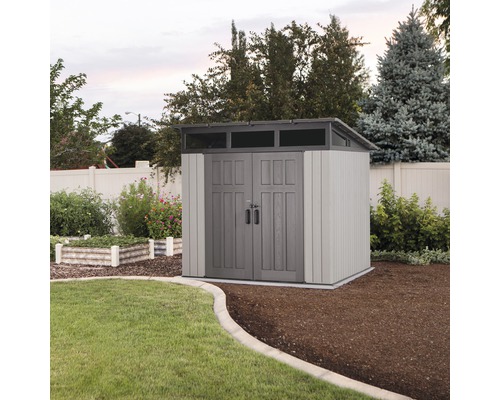 Zahradní bouda s dvoukřídlými dveřmi a světlíkem v upravené zahradě.