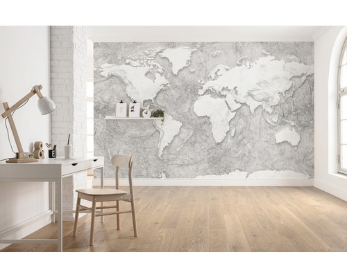 Světlá pracovna s tapetou mapy světa, psacím stolem a dřevěnou podlahou.