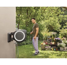 Muž používá nástěnný buben na hadici Gardena v zahradě