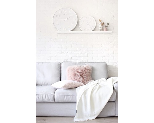 Obývací pokoj s pohovkou, polštáři, dekou a dvěma hodinami na zdi