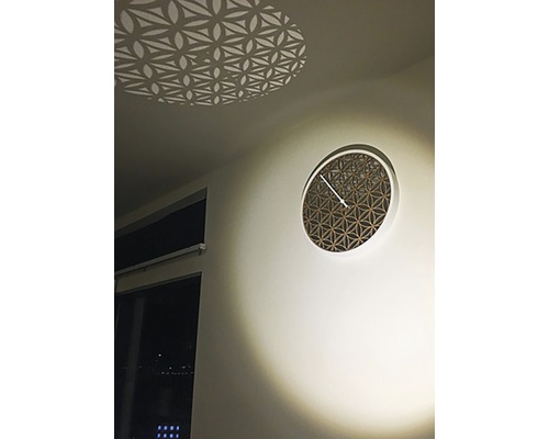 Dekorativní nástěnné hodiny s geometrickým vzorem a světelným efektem na stropě