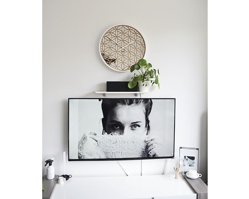 Obývací pokoj s geometrickými nástěnnými hodinami a televizí