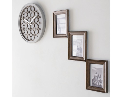 Nástěnné hodiny a tři fotorámečky na zdi