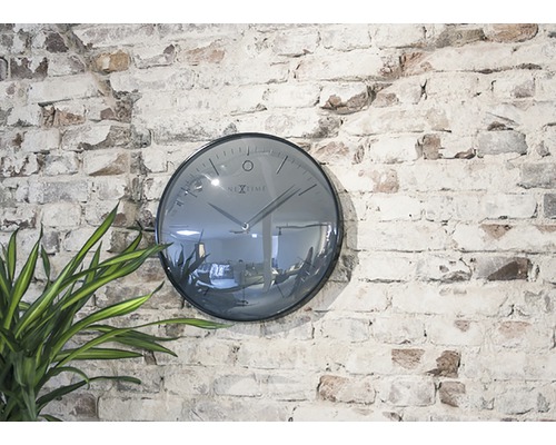Nástěnné hodiny Nextime na cihlové zdi