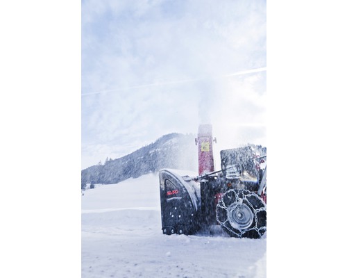 Sněhová fréza v akci před zasněženou krajinou