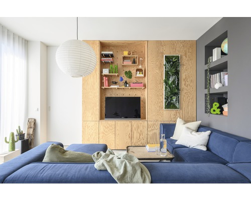 Obývací pokoj s modrou rohovou pohovkou, dřevěným obložením a dekoracemi