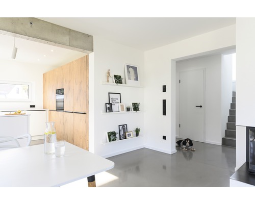 Světlý obývací pokoj s otevřenou kuchyní, jídelním stolem a dekorací na zdi