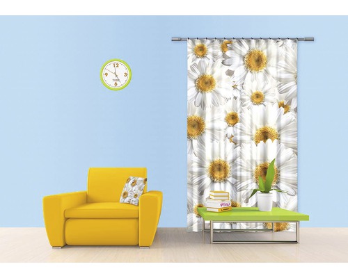 Obývací pokoj se žlutým křeslem, stolem, nástěnnými hodinami a závěsem se vzorem sedmikrásek