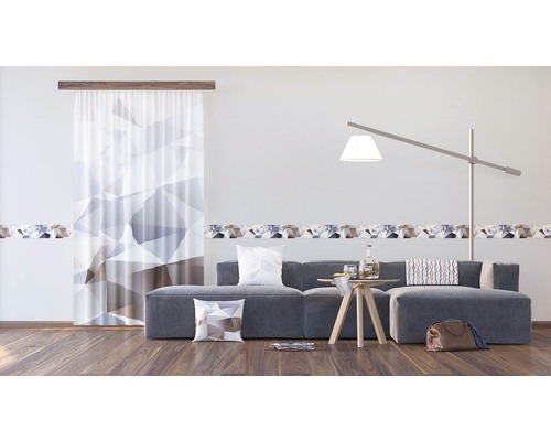 Obývací pokoj s šedou pohovkou, dekorativními polštáři, odkládacím stolkem a záclonou s geometrickým vzorem a bordurou