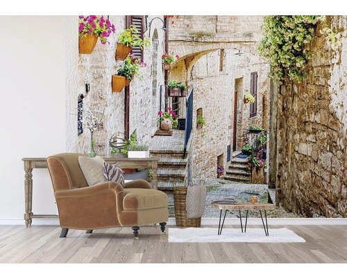Obývací pokoj s křeslem, stolem a fototapetou s uličkou v Itálii.