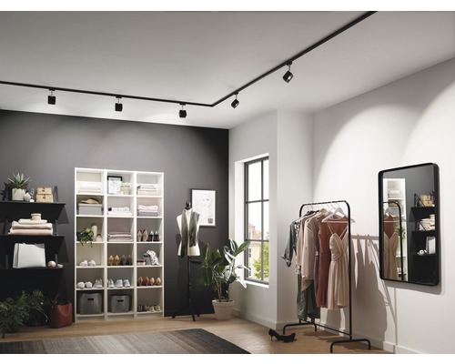 Moderní šatna s černým kolejnicovým osvětlením, regály a věšákem na oblečení