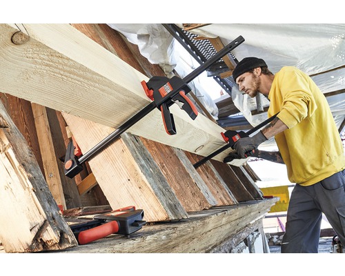 Muž upevňuje dřevo pomocí pákové svěrky