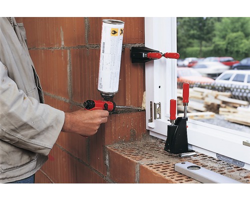 Řemeslník utěsňuje okno pěnovou pistolí