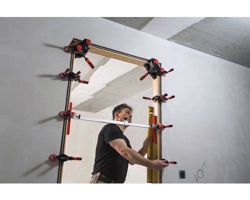 Muž montuje zárubeň pomocí zarovnávacích svorek