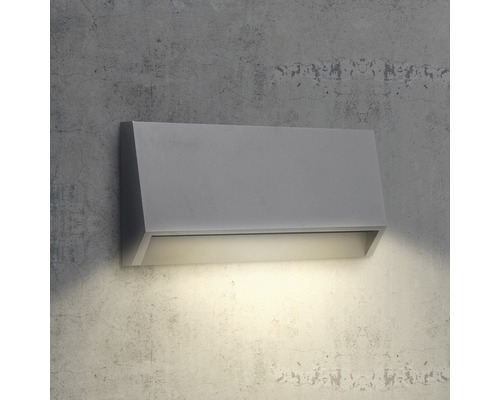 Šedé nástěnné svítidlo se světlem směřujícím dolů na betonové zdi