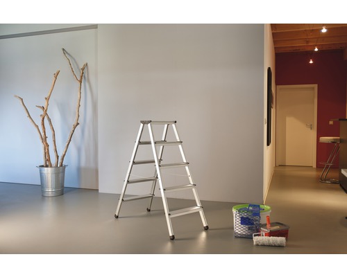 Pohled do místnosti s hliníkovým žebříkem, kbelíkem s větvemi a malířskými potřebami