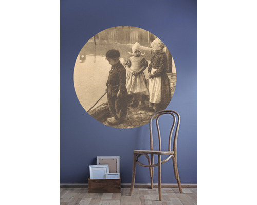 Nástěnná dekorace s dětskou samolepkou na zeď a dřevěnou židlí vedle dřevěné krabice s rámečky na fotografie