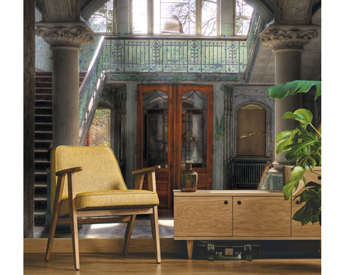 Interiérová fotografie místnosti s křeslem, skříňkou a dekoracemi v budově se schodištěm