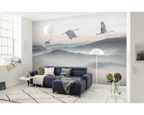 Obývací pokoj s fototapetou horské krajiny a jeřábů, pohovka, koberec a dekorace.