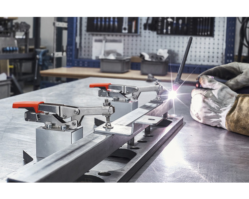 Dílenská scéna se svařováním a fixací obrobku pomocí rychloupínáku