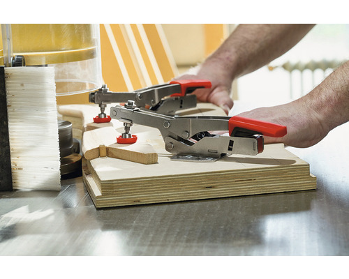 Dva pákové svorky upevňují kus dřeva.