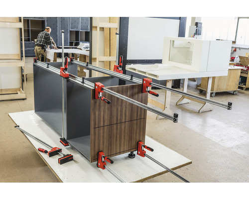 Pracovní stůl s dřevěnou zásuvkou a šroubovacími svorkami během montáže