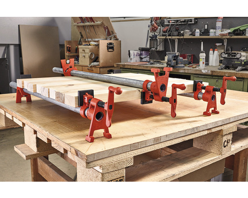 Dřevěné desky jsou upevněny trubkovými svorkami na pracovním stole.