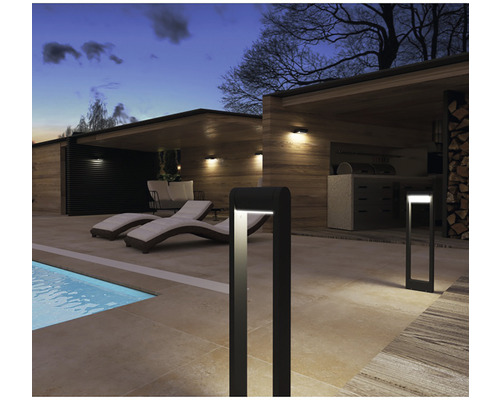 Scéna s venkovním osvětlením, lehátky u bazénu a venkovní kuchyní.