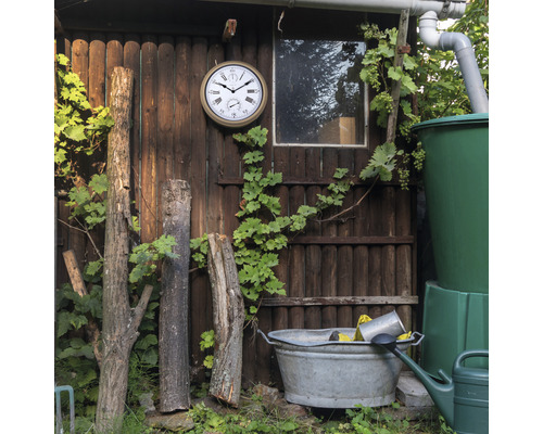 Zahradní domek s hodinami, sudem na dešťovou vodu a zinkovou vanou na zahradě