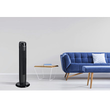 Scéna s věžovým ventilátorem, pohovkou a odkládacím stolkem v světlém obývacím pokoji.