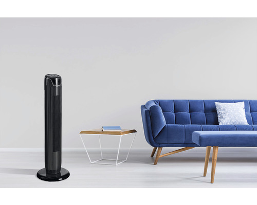Scéna s věžovým ventilátorem, pohovkou a odkládacím stolkem v světlém obývacím pokoji.